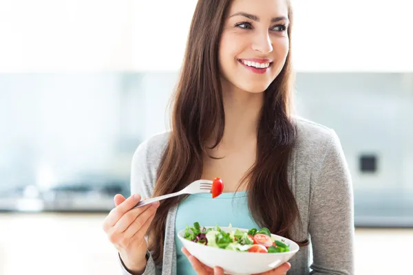 Femme souriante préparant une salade fraîche